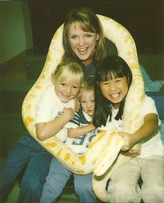 Mother and three children holding an albino python
