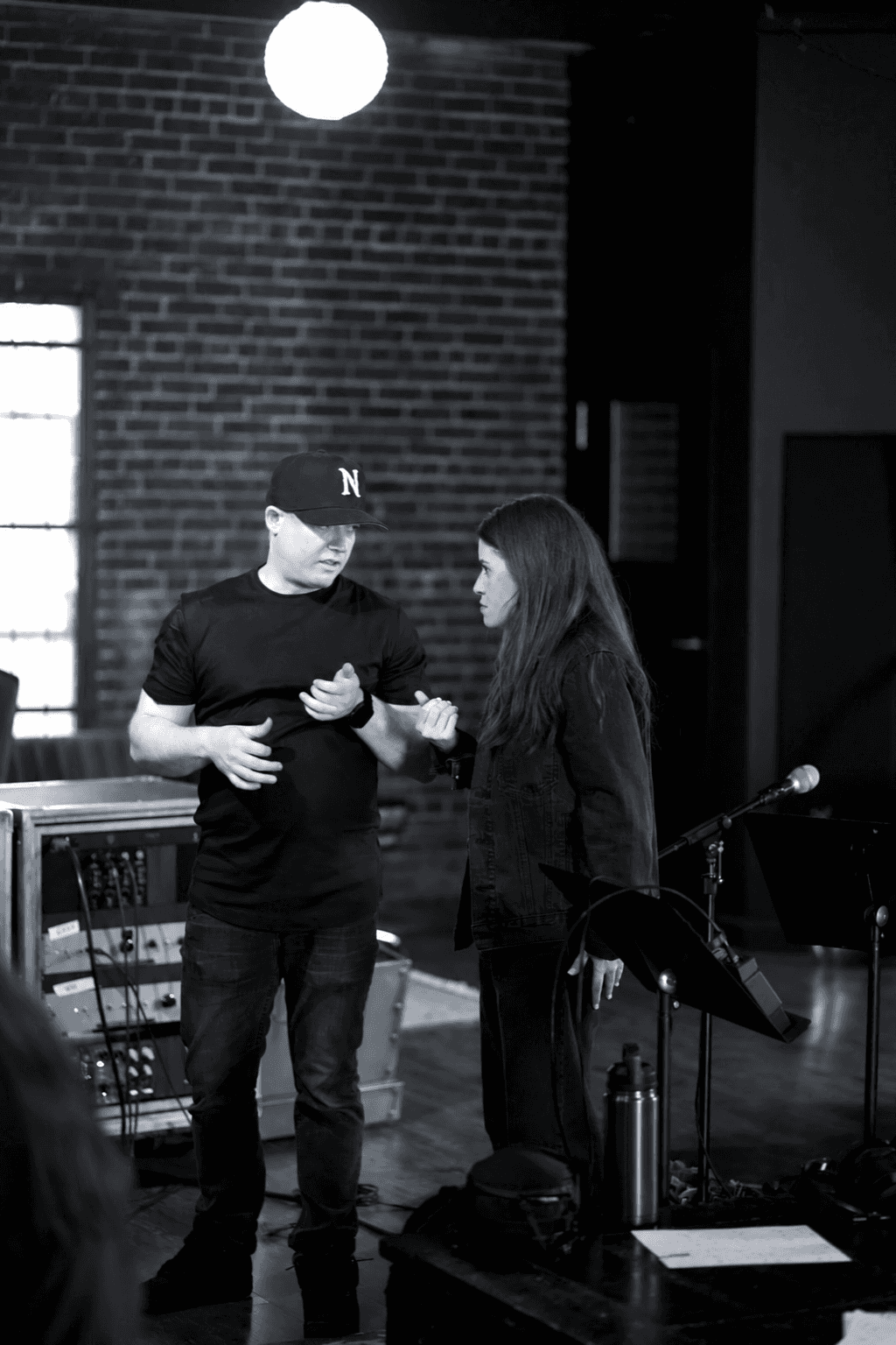 Brandon Metcalf talks through a part with an artist beside the control-room window.