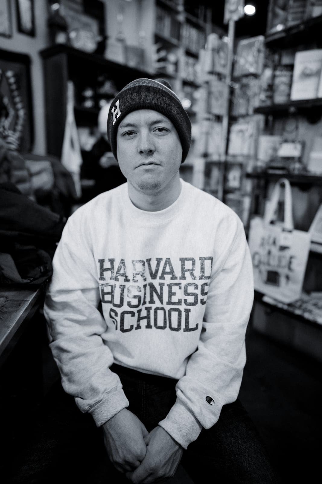 Brandon Metcalf in a Harvard Business School sweatshirt and beanie, seated in a shop.