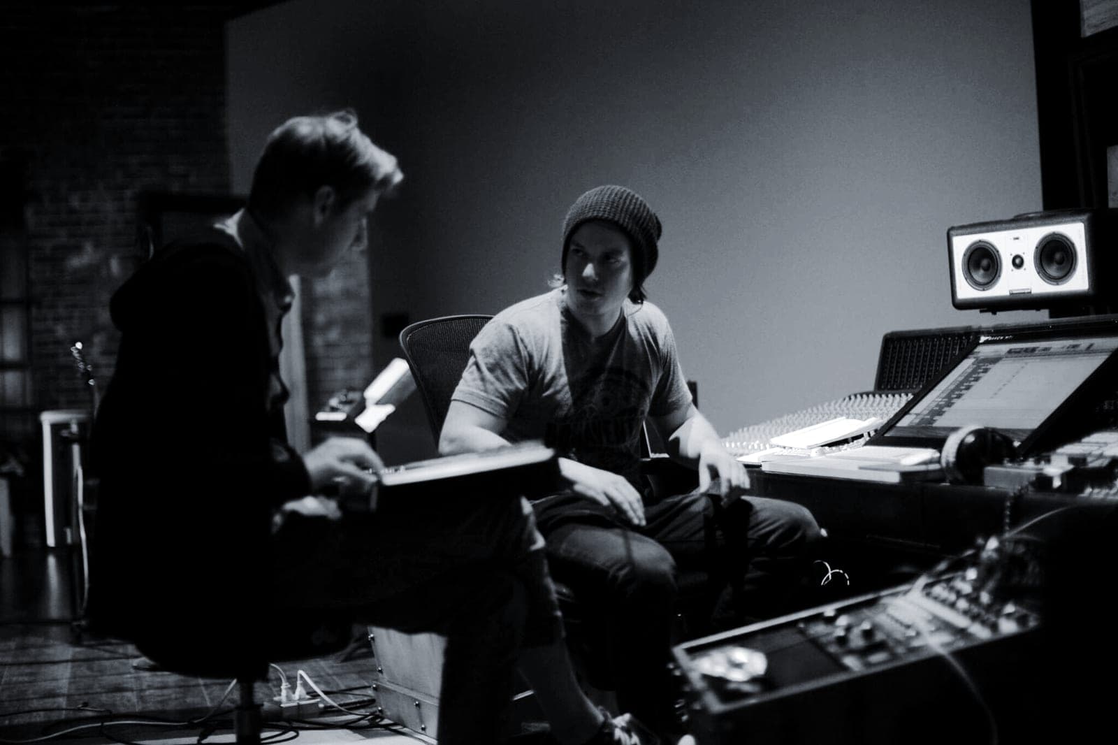 Two musicians work side by side at the studio desk during a session.