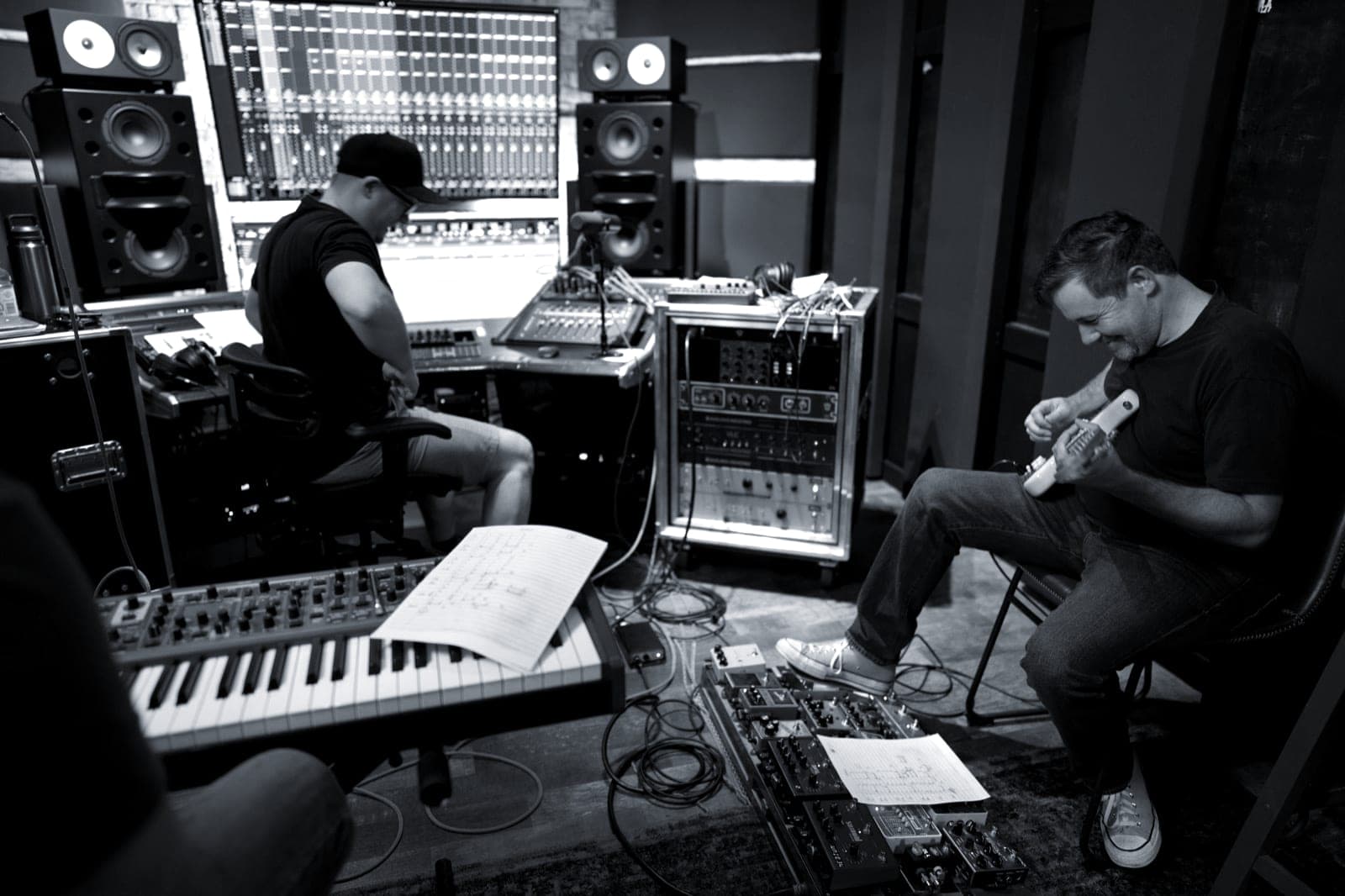 A guitarist, a keys player, and Brandon Metcalf at the desk work through a tracking session.