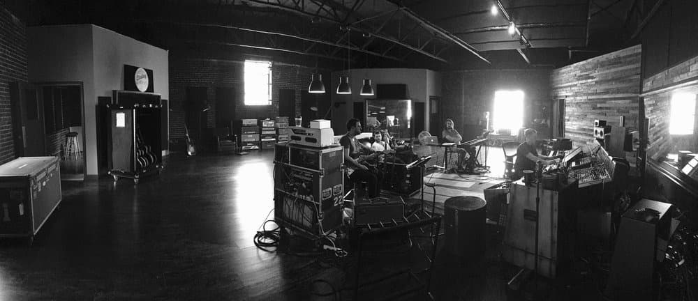 Black-and-white panorama of a full band recording in the finished studio