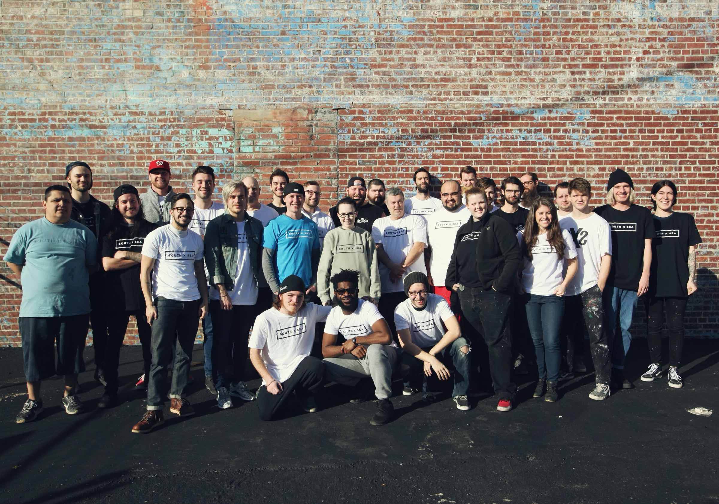 The South x Sea team together in front of the brick warehouse wall