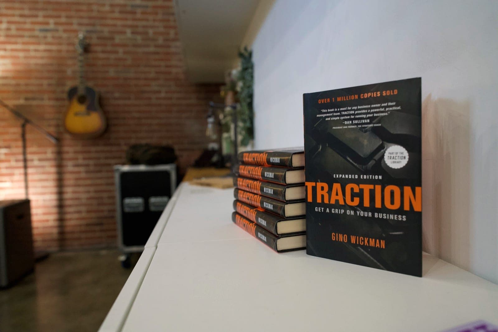 Copies of Traction stand on the session-room counter, with a guitar on the brick wall behind them.